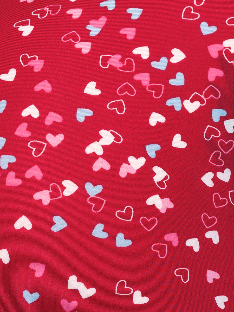 Closeup view of red fabric showing a multicolored heart pattern
