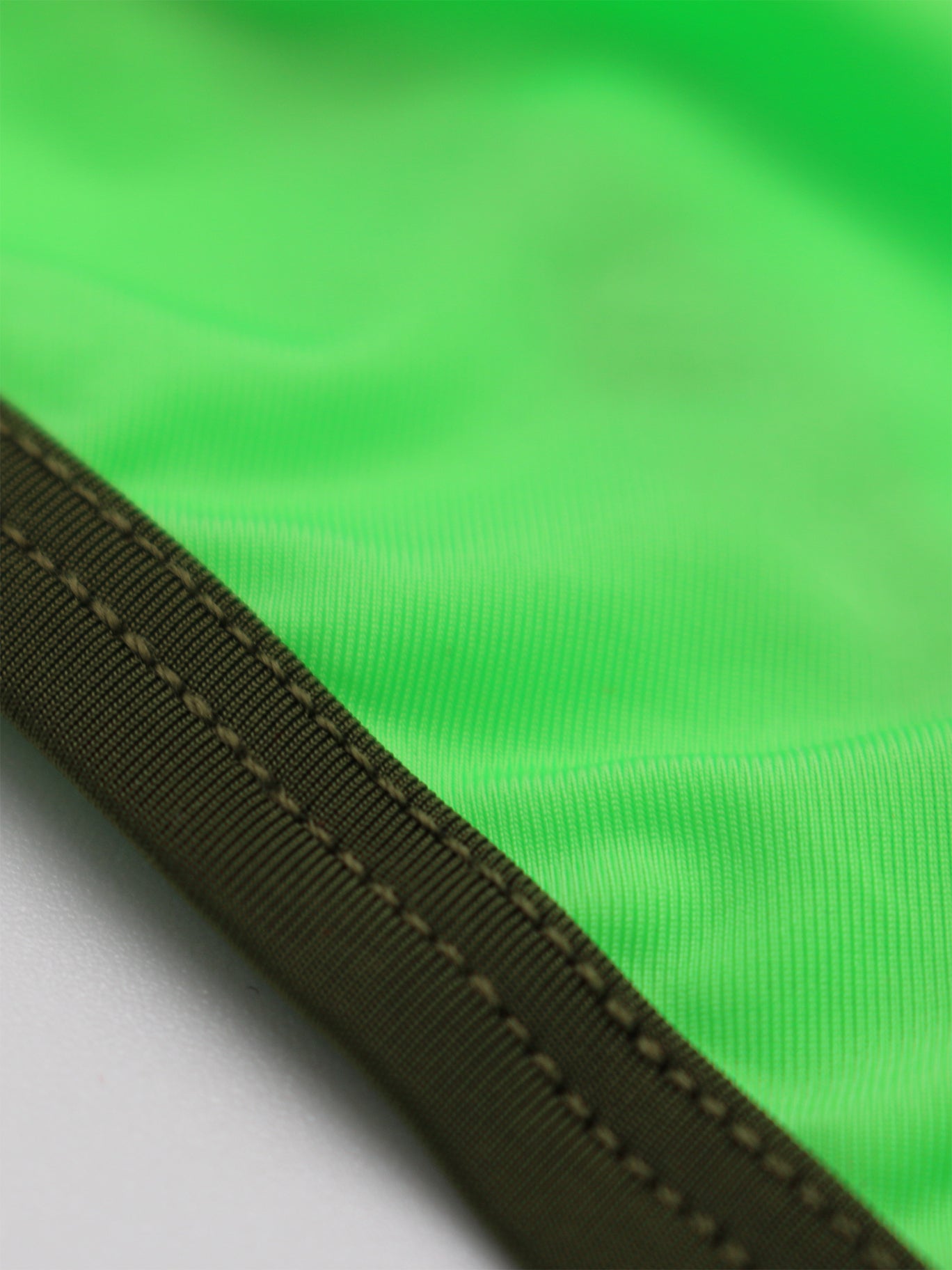 Close-up of green fabric with an olive trim on a white background