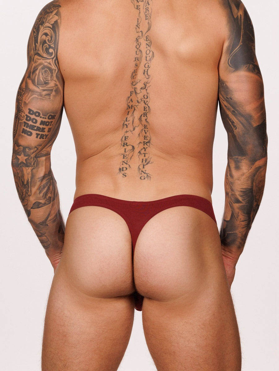 Back view of a male model wearing a burgundy red Body Aware thong