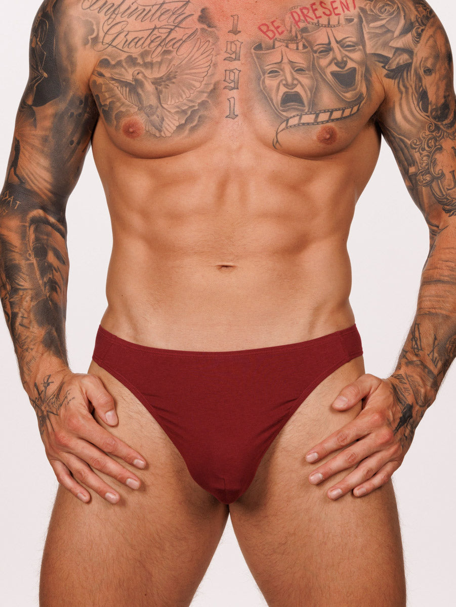 Front view of a male model wearing a burgundy red Body Aware thong