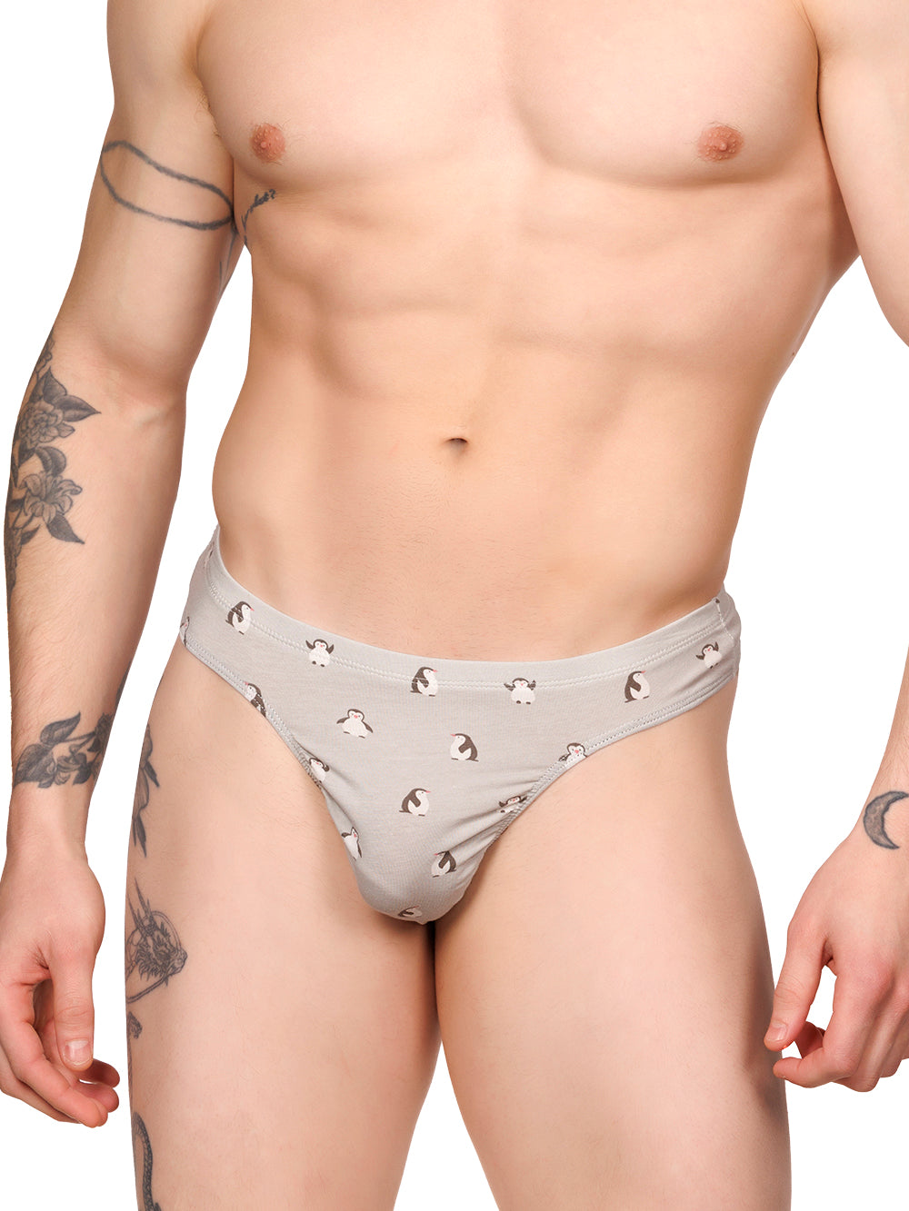 Front view of a male model wearing a grey Body Aware thong with a penguin print pattern