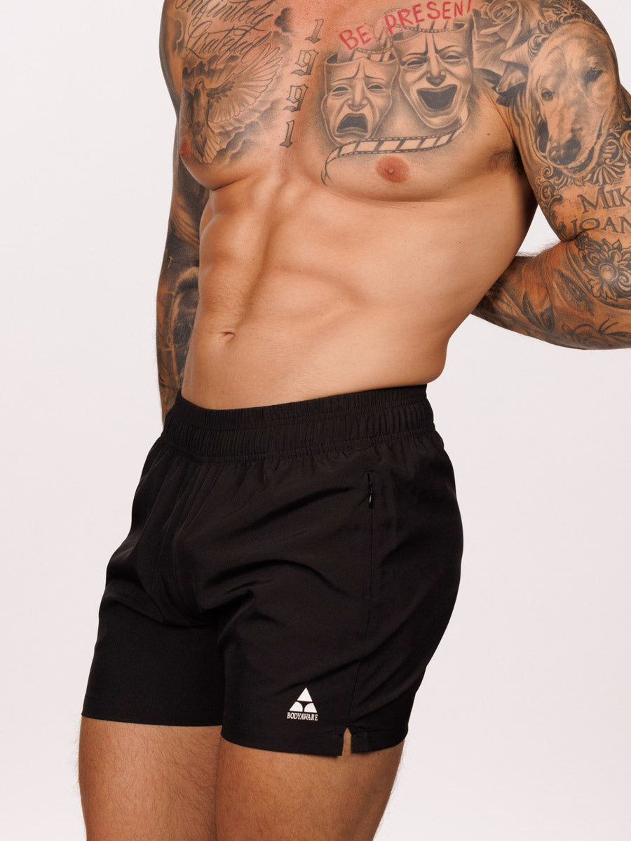 Side view of a male model wearing black Body Aware athletic shorts