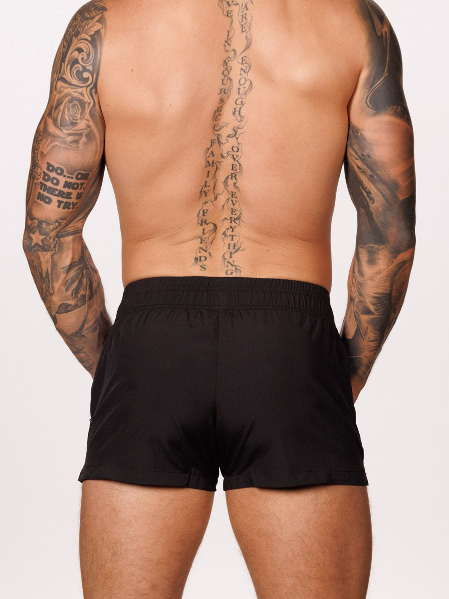 Back view of a male model wearing black Body Aware gym shorts