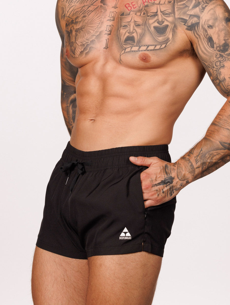 Side view of a male model wearing black Body Aware gym shorts with drawstring and pocket