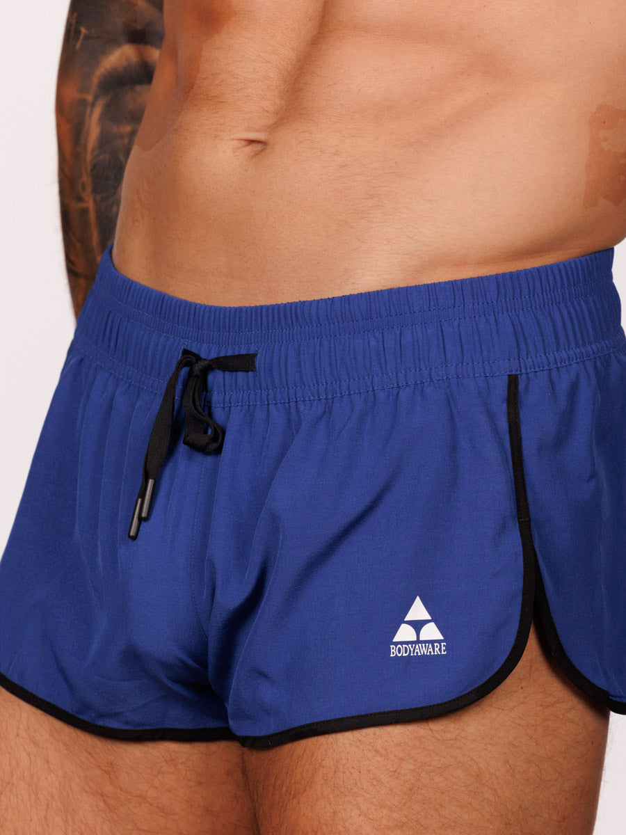 Closeup view of a male model wearing blue Body Aware side split shorts