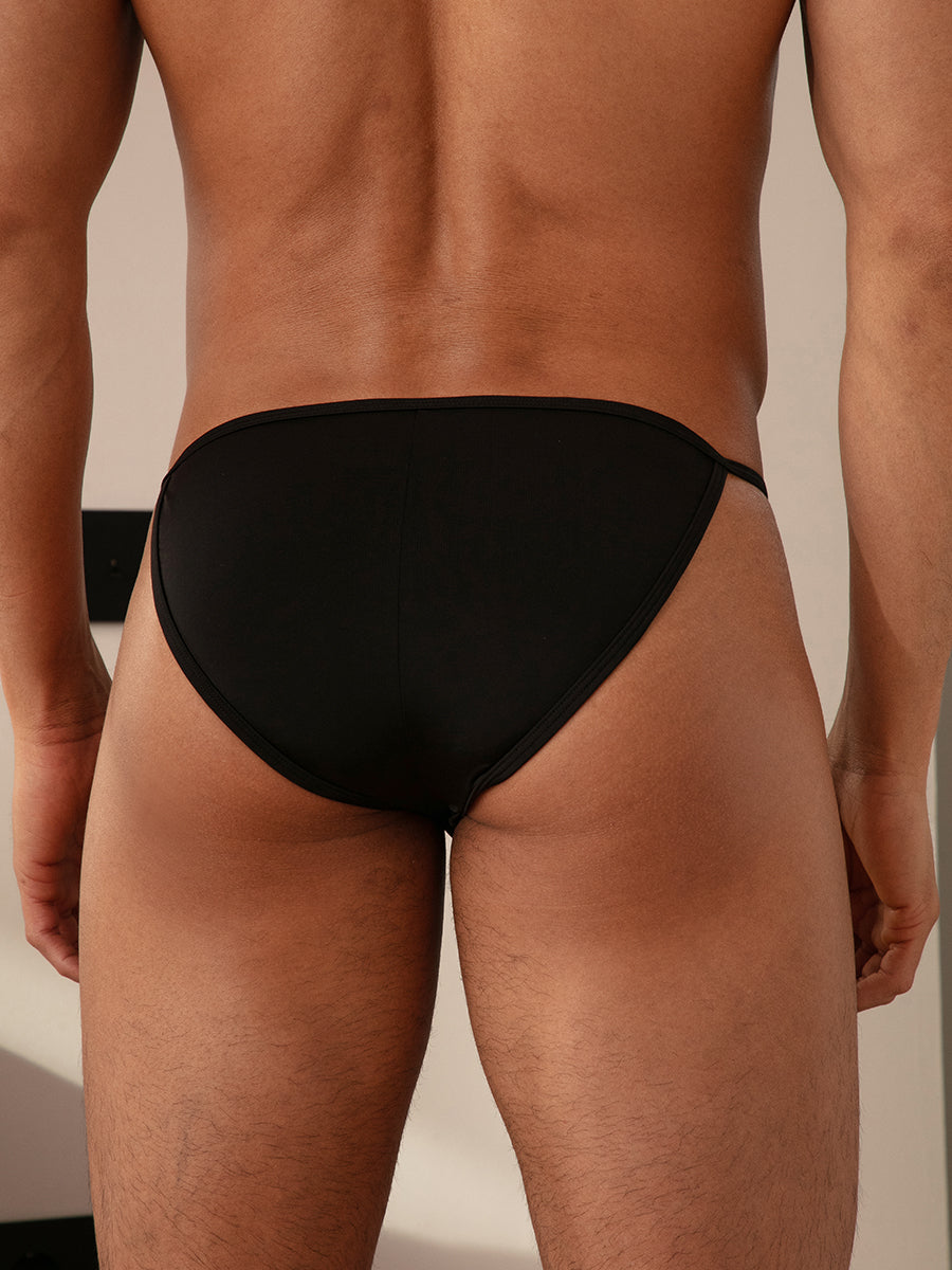 Closeup rear view of a man posing in black nylon bikini briefs.