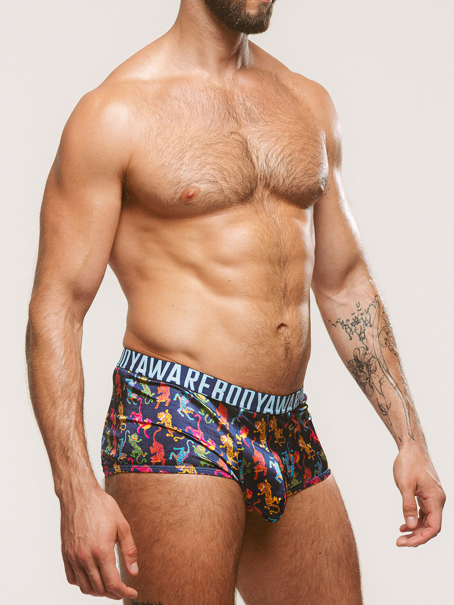 Side view of a man wearing navy blue satin boxers with a Body Aware branded waistband