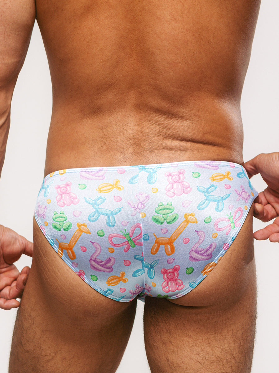 Back view of a man wearing light blue satin briefs with a colorful balloon animal print.