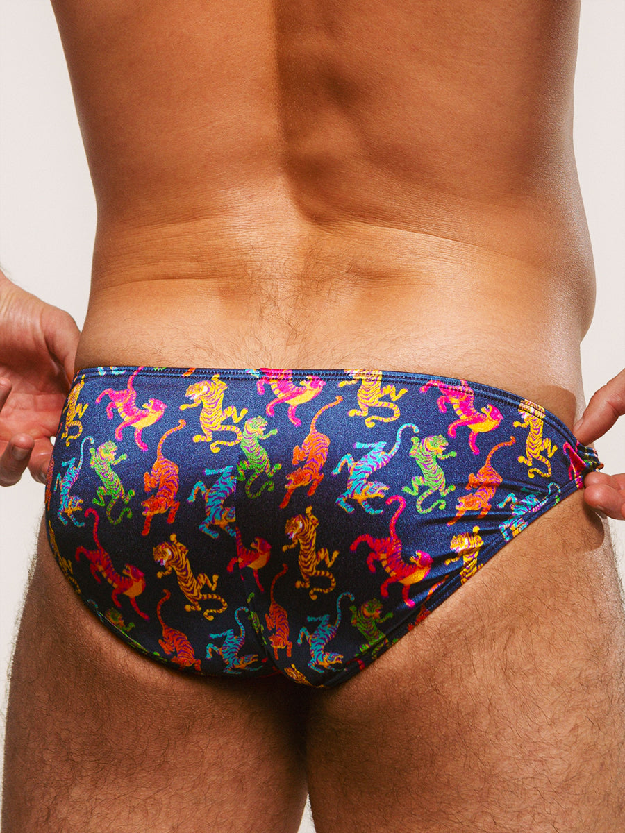 Back view of a man wearing a navy pair of briefs on a plain background