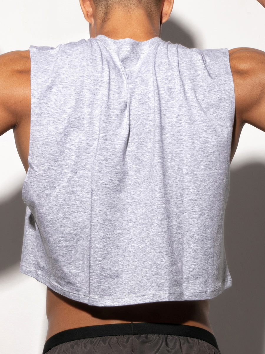 Man wearing a gray sleeveless top with a plain background