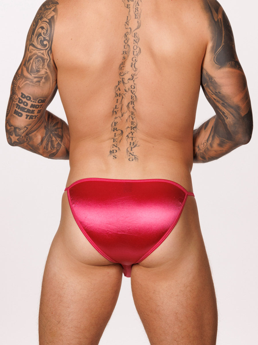 Back view of a male model wearing a pink satin Body Aware bikini brief