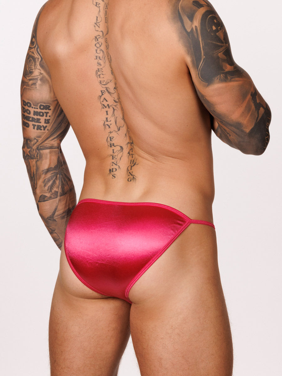 Back view of a male model wearing a pink satin Body Aware bikini brief