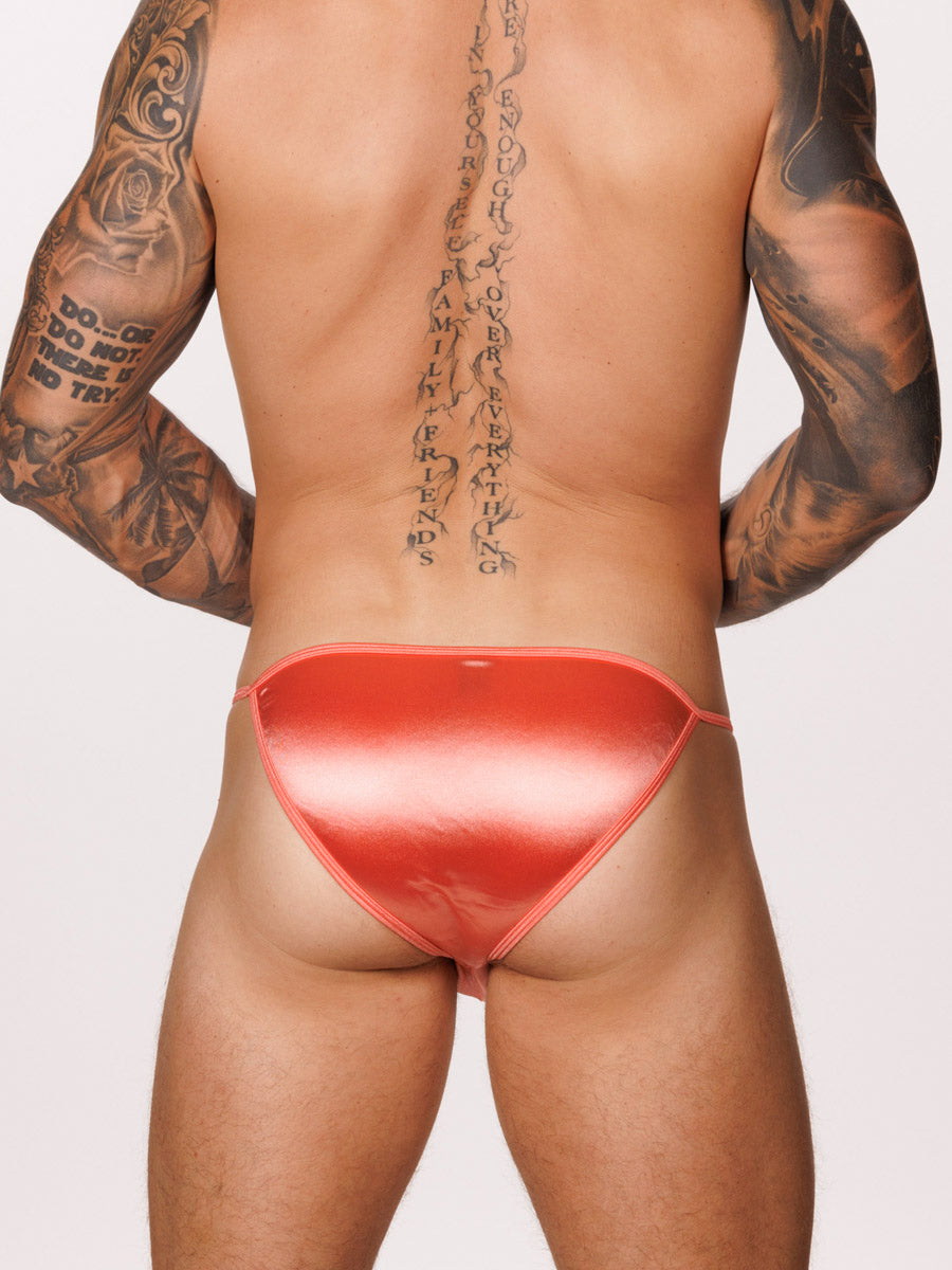 Back view of a male model wearing a peach satin Body Aware bikini brief