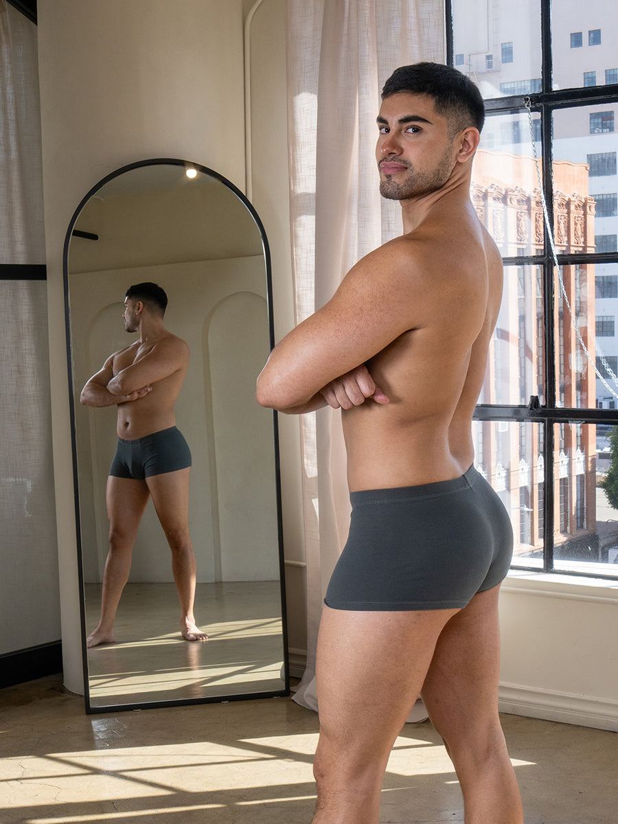 A man wearing grey Body Aware boxers standing in front of a mirror. 