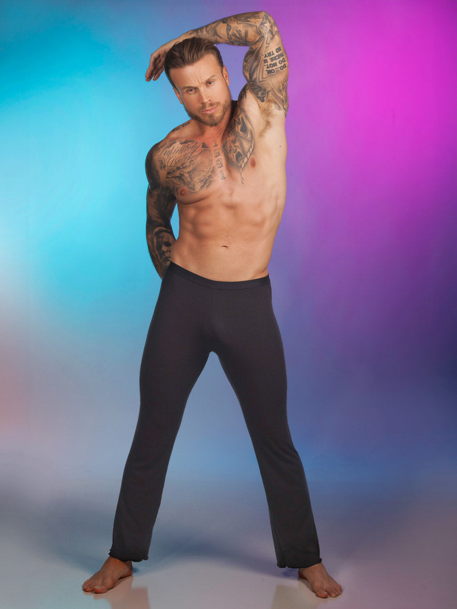 A male model wearing black Body Aware lounge pants against a pink and blue background