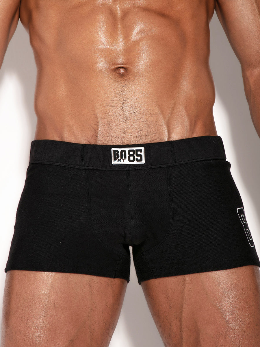 Black booty shorts with a brand logo on a neutral background