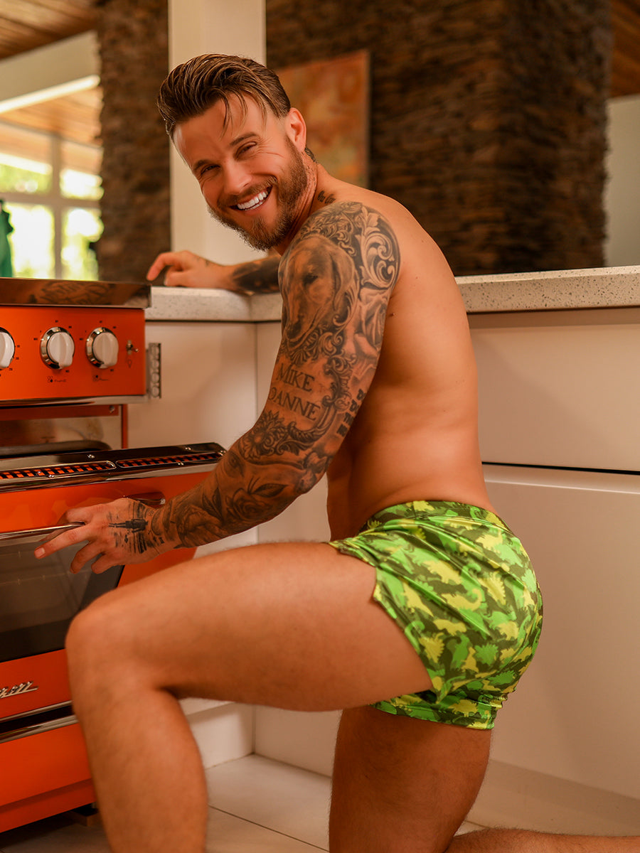 Side view of a male model wearing green Body Aware shorts in front of an oven