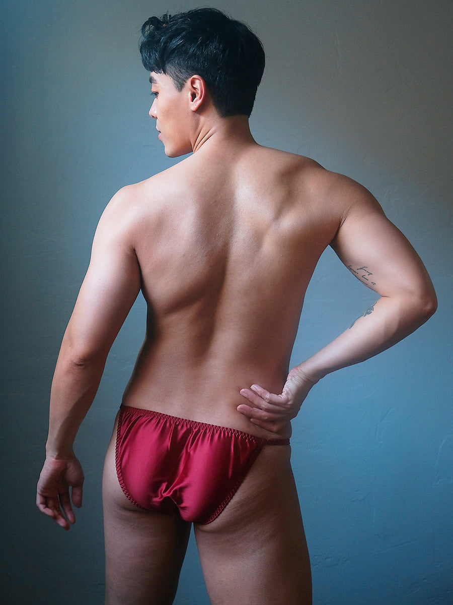 Back view of a male model wearing a Body Aware burgundy bikini brief