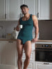 Video of a man wearing a teal green tank top and matching Body Aware briefs, standing in a kitchen.